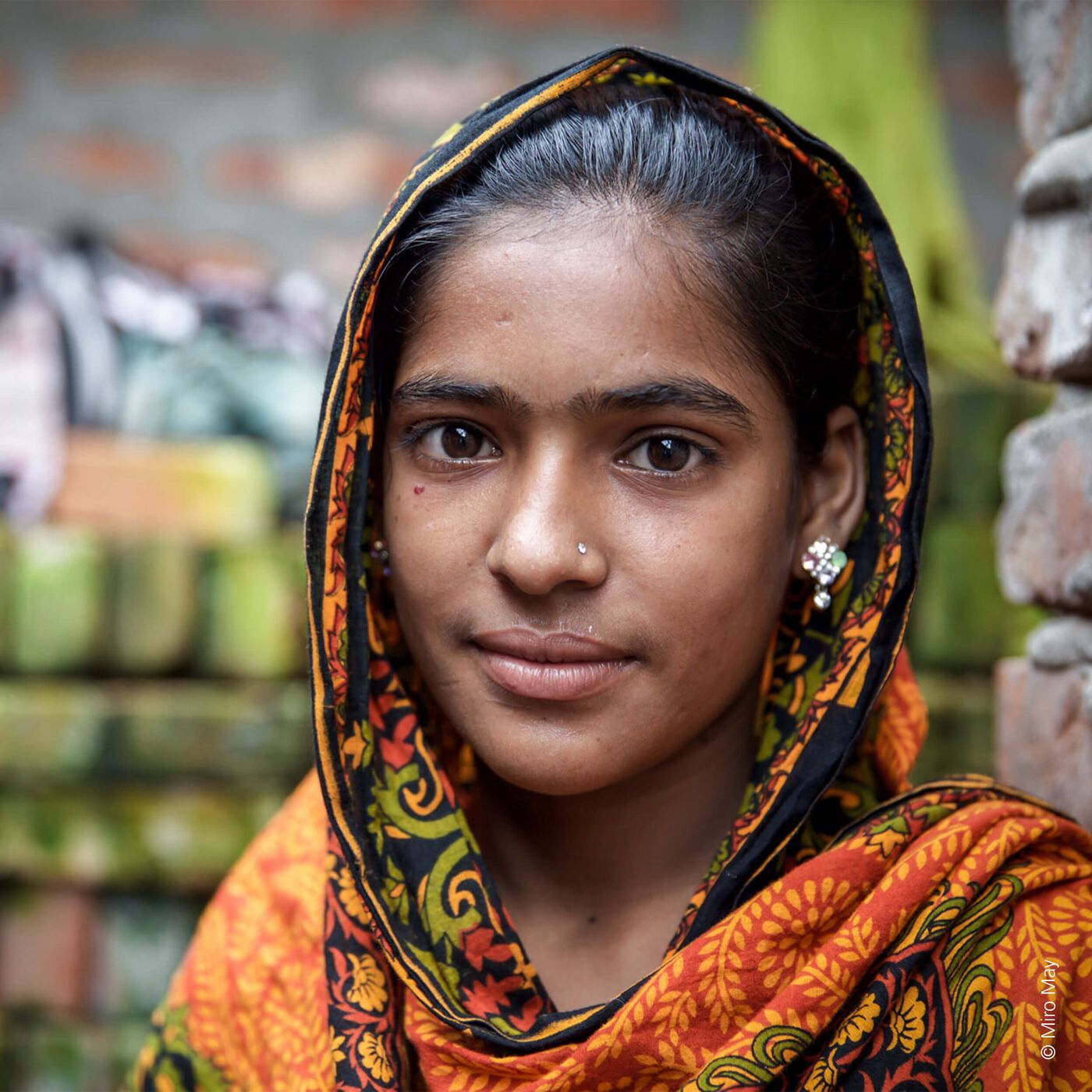 Ein Mädchen trägt einen bunten Schal und lächelt fröhlich in die Kamera.