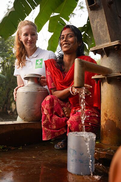 Ärztin der German Doctors mit einer Frau an einer Wasserstelle in Indien