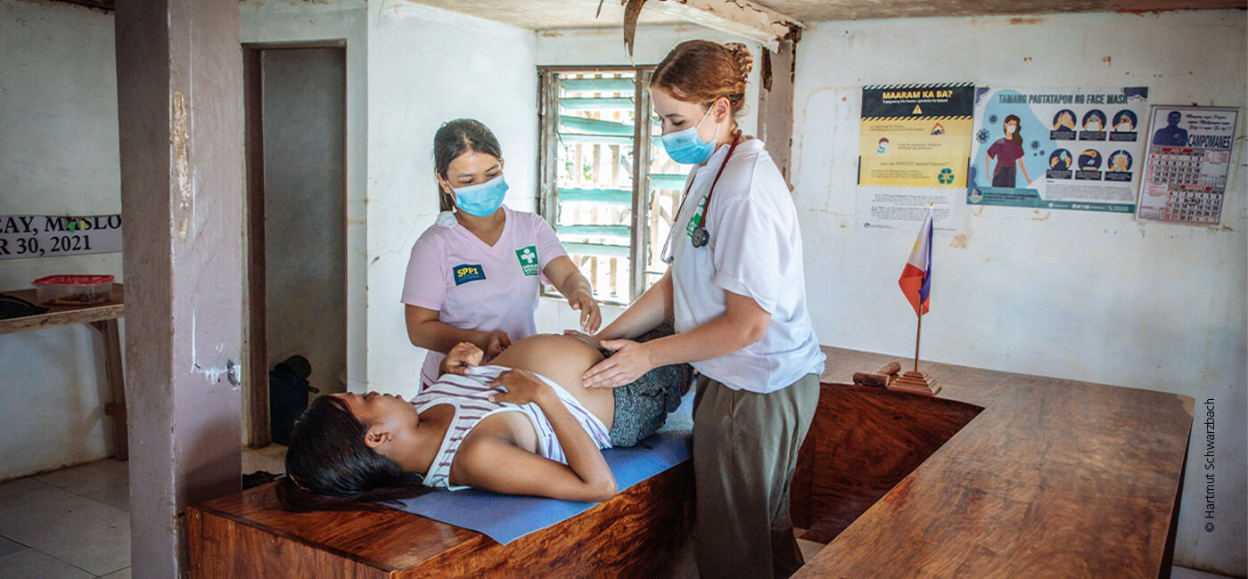 Eine schwangere Frau liegt und wird von zwei Ärztinnen untersucht